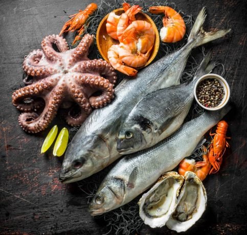Fresh seafood with spices and lime slices. On dark rustic background